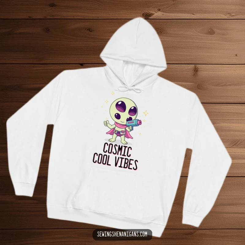 Funny kawaii alien waving a ray gun that shoots sparkles, a humorous and cozy design on this hoodie, ideal for chilling.
