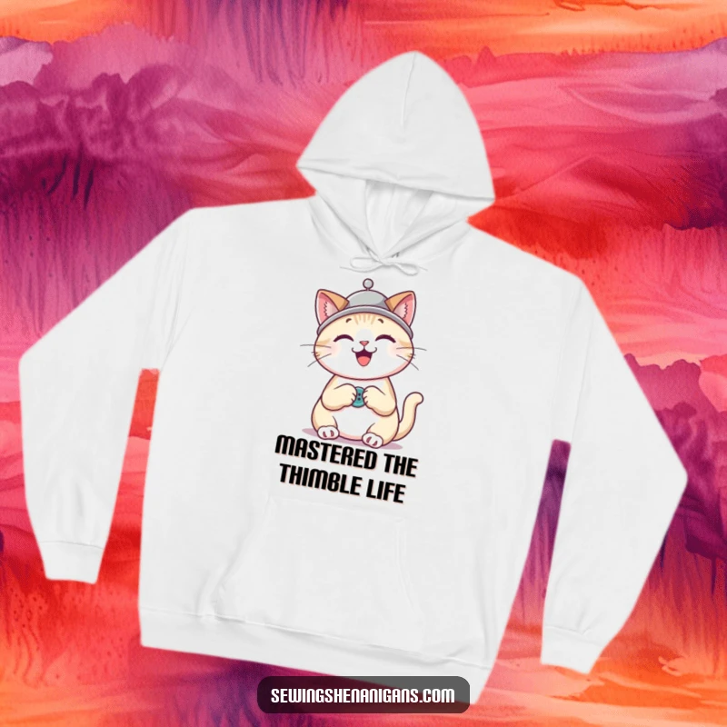 Funny cat wearing a thimble hat, happily sewing a button, depicted on a soft and cozy hoodie.
