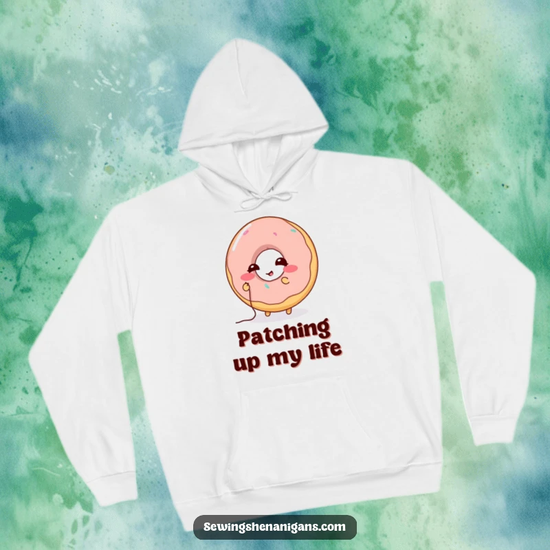 Funny Donut Stitching Hoodie: A giggling donut character attempts to mend a hole with thread, perfect for a funny and cozy gift.