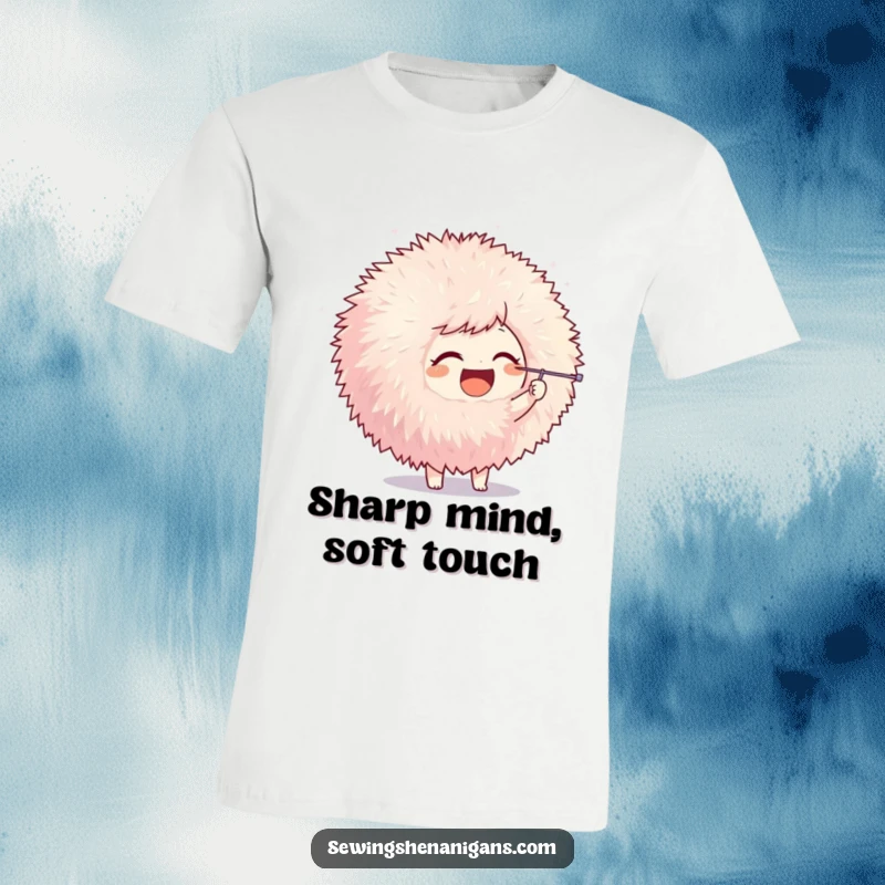 Funny t-shirt depicting a joyful character poking a giant fluffy pom-pom with a needle, illustrating playful crafting.